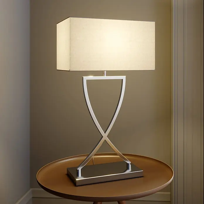 Lucande Tischleuchte Evaine - L x B x H: 20 x 35 x 66 cm, chrom / silber, weiß / opal, E27 - Beleuchtete moderne silberne Tischlampe mit sanduhrförmigem Fuß und rechteckigem weißen Schirm auf einem runden Tisch.