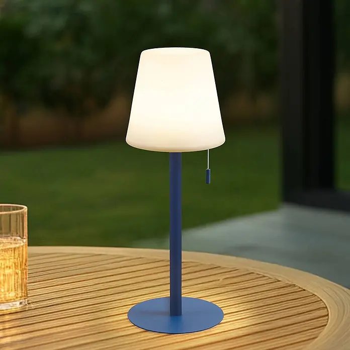 Lindby Tischleuchte Azalea - L x B x H: 16,5 x 16,5 x 45 cm, blau - Blaue Outdoor-Tischleuchte mit weißem Schirm, beleuchtet auf einem Holztisch im Garten.