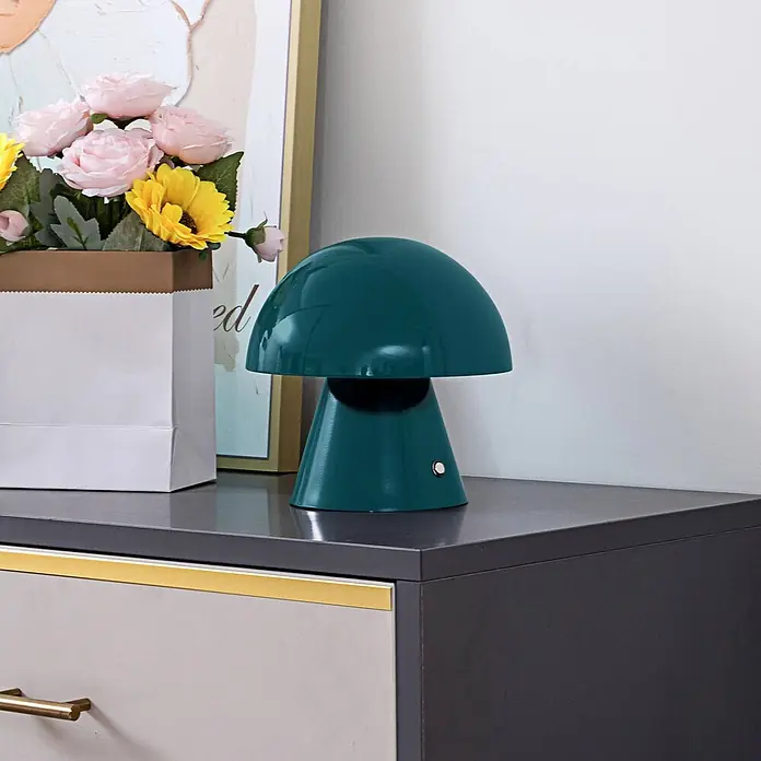 Lindby Tischleuchte Nevijo - L x B x H: 18 x 18 x 17,5 cm, grün, grün - Glänzende dunkelgrüne Pilz-Tischlampe auf einer dunkelgrauen Kommode, neben einem weißen Beutel mit Blumen.