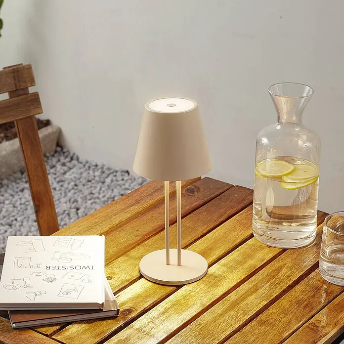 Lindby Tischleuchte Janea - creme / amber, creme / amber - Beige Tischlampe mit konischem Schirm und zwei Stützen steht auf einem Holztisch.