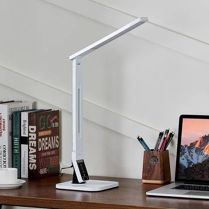 Lindby Tischleuchte Eleni - L x B x H: 18 x 17,2 x 45 cm, weiß / opal, weiß / opal - Weiße, schlanke LED-Schreibtischlampe mit verstellbarem Arm und Touch-Bedienelementen auf einem Holzschreibtisch mit Büchern und Laptop.
