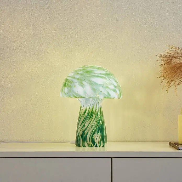 Lindby Tischleuchte Hubi - L x B x H: 22 x 22 x 28 cm, grün, grün, E27 - Grün-weiß gesprenkelte Glas-Pilz-Tischleuchte, beleuchtet auf einer weißen Kommode.