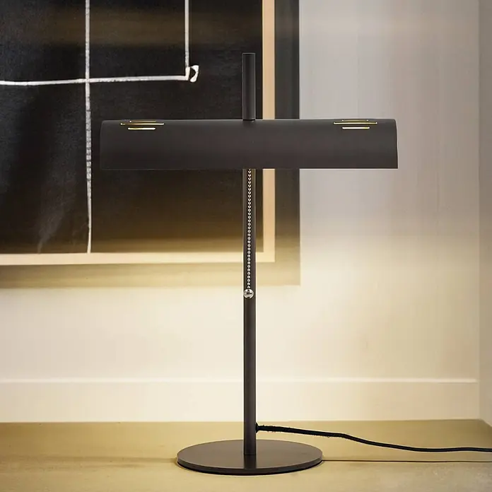 Lucande Tischleuchte Nysira - L x B x H: 18 x 36 x 50 cm, schwarz, schwarz, E27 - Dunkle Metall-Tischlampe mit rechteckigem Schirm und schlankem Stand, beleuchtet eine Raumecke.