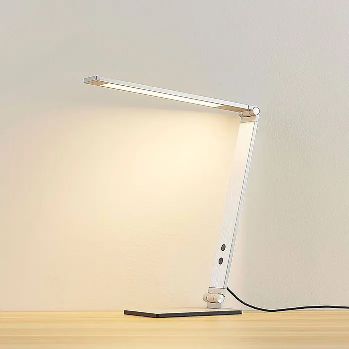 Lucande Tischleuchte Nicano - L x B x H: 34,5 x 12 x 39 cm, alu / grau / zink, alu / grau / zink - Moderne silberne LED-Schreibtischlampe mit verstellbarem Arm und Kopf, die warmweißes Licht auf einem Holzschreibtisch spendet.