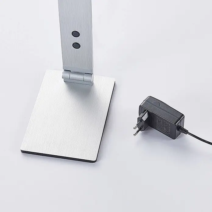 Lucande Tischleuchte Nicano - L x B x H: 34,5 x 12 x 39 cm, alu / grau / zink, alu / grau / zink - Gebürstete silberne Schreibtischlampenbasis und -arm mit Bedientasten, daneben ein schwarzes Netzteil.
