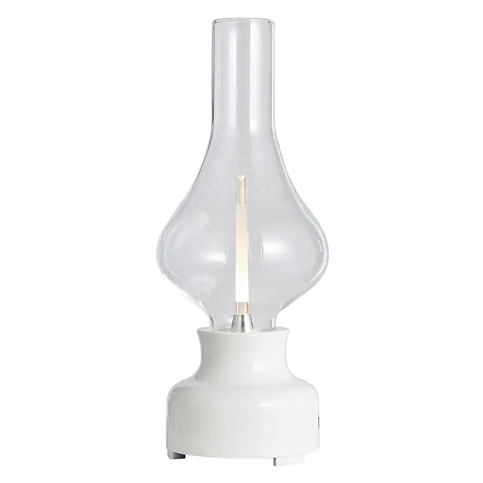 Lindby Tischleuchte Maxentius - L x B x H: 12 x 12 x 30 cm, creme / amber, klar / transparent - Eine moderne Lampe mit klarem Glaszylinder über einem beleuchteten Leuchtelement auf einem weißen Keramiksockel.