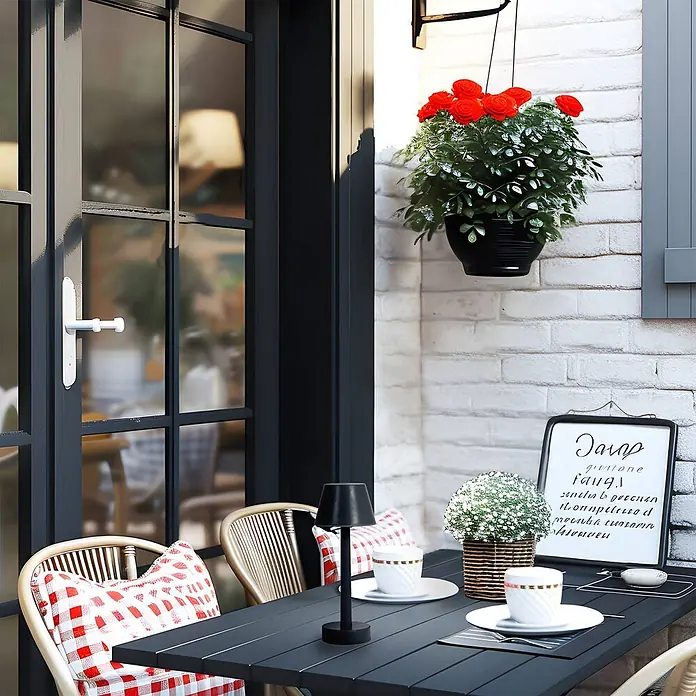 Lindby Tischleuchte Gaja - schwarz, schwarz - Schwarzer Outdoor-Tisch mit Lattenplatte und Rattanstühlen mit roten Karokissen auf einer Terrasse.