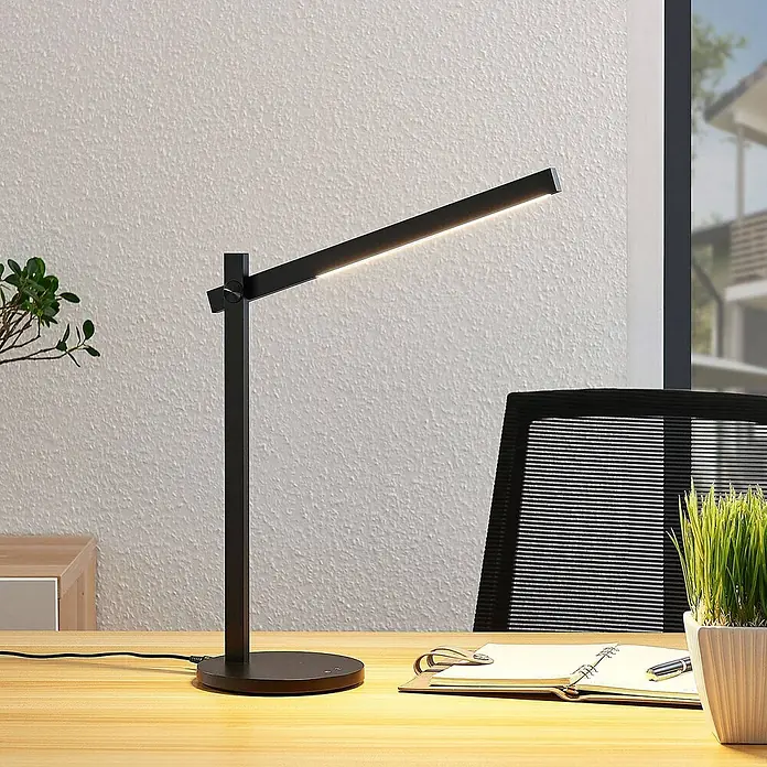 Lindby Tischleuchte Loretta - L x B x H: 40,8 x 17 x 43 cm, schwarz, schwarz - Moderne schwarze LED-Schreibtischlampe mit verstellbarem Arm, die einen Holzschreibtisch beleuchtet.