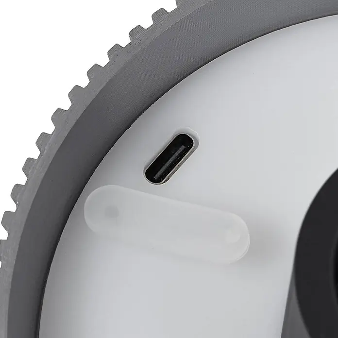 Lindby Tischleuchte Linor - L x B x H: 11,3 x 11,3 x 8,8 cm, alu / grau / zink - Nahaufnahme eines weißen Geräts mit grauem Zahnriemen, schwarzer USB-C-Ladebuchse und durchscheinender Schutzklappe.