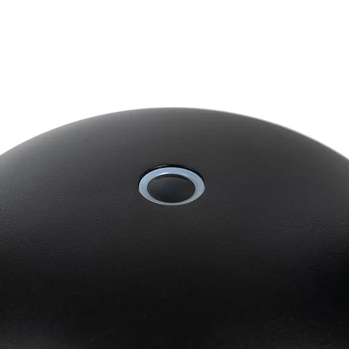 Arcchio Tischleuchte Thenra - schwarz, schwarz - Nahaufnahme einer schwarzen, texturierten Oberfläche mit einem runden Knopf und einem lichtdurchlässigen Ring.