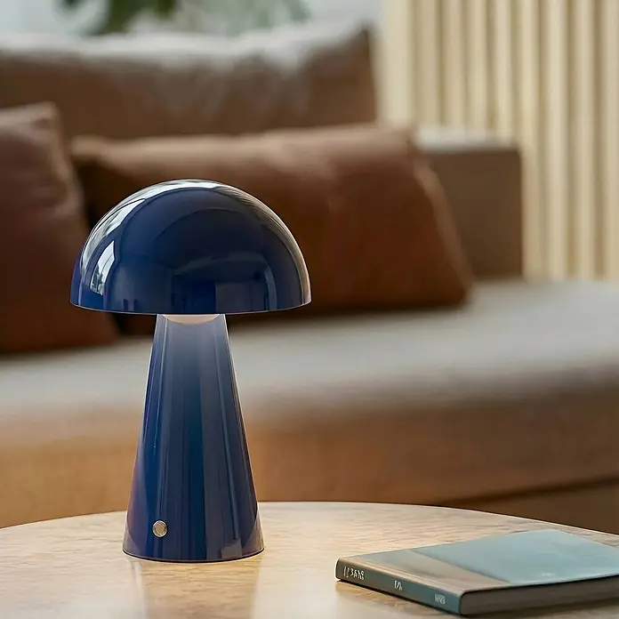 Lindby Tischleuchte Nevijo - L x B x H: 20 x 20 x 30 cm, blau, blau - Eine glänzende, blaue pilzförmige Tischlampe auf einem Tisch in einem unscharfen Wohnzimmerambiente.
