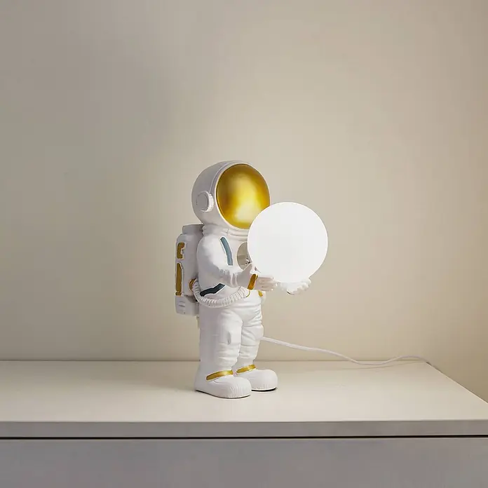 Lindby Tischleuchte Kosmo - L x B x H: 22,5 x 14 x 31 cm, weiß / opal, weiß / opal, G9 - Weiße Astronautenfigur-Lampe mit goldenem Visier und Akzenten, die eine leuchtende weiße Kugel hält.