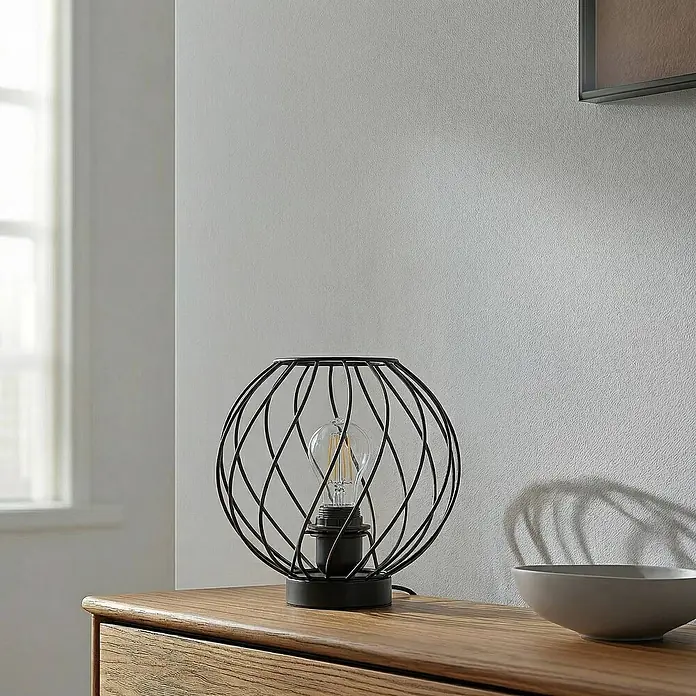 Lindby Tischleuchte Danika - schwarz, E27 - Schwarze Metallkäfig-Tischlampe mit sichtbarer Glühbirne auf einem Holznachttisch.