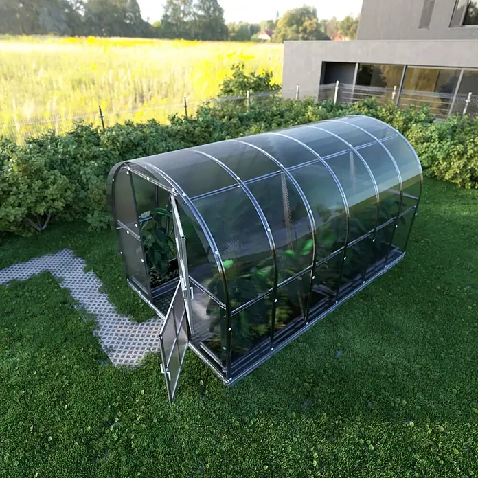 Klasika Greenhouses Gewächshaus Arch Klasika - Außenmaß inkl. Dachüberstand (B x T): 300 x 400 cm, Material Seitenwand: Kunststoff, 4 mm, Silbergrau - Ein stabiles, gewölbtes transparentes Gewächshaus mit silbernem Rahmen, bepflanzt, Tür offen, neben einem gepflasterten Weg.