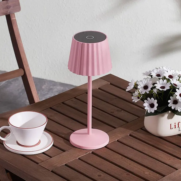 Lindby Tischleuchte Esali - L x B x H: 11 x 11 x 28,5 cm, violett / pink / rose, violett / pink / rose - Rosa gerippte Tischlampe mit rundem Fuß und dunkler Oberseite auf einem Holzlamellentisch.