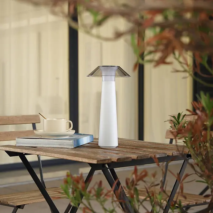 Lindby Tischleuchte Gomba - weiß / opal - Moderne weiße Tischlampe mit transparentem kegelförmigem Schirm, auf einem Holztisch.
