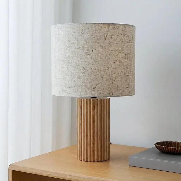 Lindby Tischleuchte Kimiko - L x B x H: 25 x 25 x 38 cm, Holz hell, E27 - Geriffelte Tischlampe aus Naturholz mit hellem Stoffschirm auf einer Holzoberfläche.