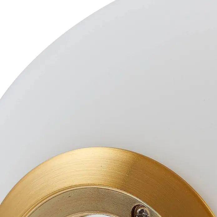 Lindby Tischleuchte Kirstan - creme / amber, weiß / opal, E27 - Nahaufnahme eines weißen, lichtdurchlässigen Diffusors und eines gebürsteten Messingrings mit sichtbarer Schraube, Teil einer Leuchte.