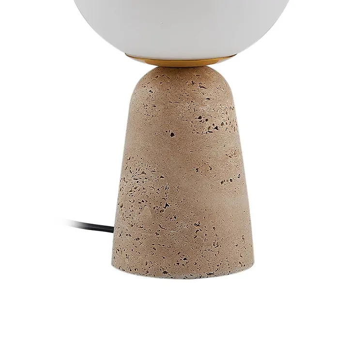 Lindby Tischleuchte Kirstan - creme / amber, weiß / opal, E27 - Tischlampe mit texturiertem hellbraunem Steinsockel, weißem Kugelschirm und Goldring. Ein schwarzes Netzkabel ist sichtbar.