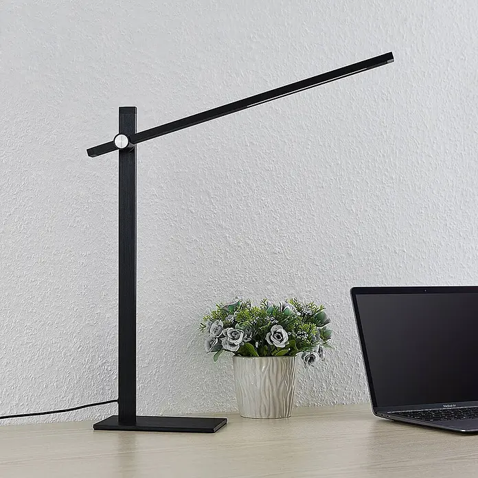 Lucande Tischleuchte Wasko - L x B x H: 45,5 x 12 x 47 cm, schwarz, schwarz - Moderne schwarze LED-Schreibtischlampe mit schlankem Design und silbernem Drehknopf, auf einem Schreibtisch neben einem Laptop.