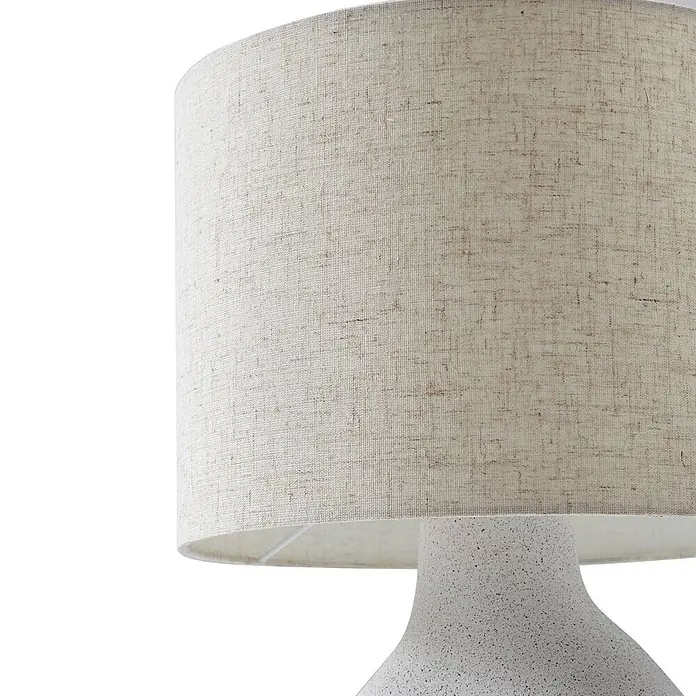 Lindby Tischleuchte Thalassia - weiß / opal, weiß / opal, E27 - Nahaufnahme einer Lampe mit hellem, strukturiertem Stoffschirm und gesprenkeltem weißem Keramiksockel.