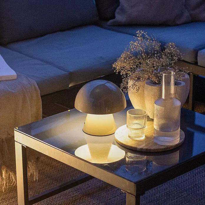 Lindby Tischleuchte Nevijo - alu / grau / zink, alu / grau / zink - Pilzförmige Tischlampe mit warmem Licht auf einem Glastisch, spendet Umgebungsbeleuchtung.