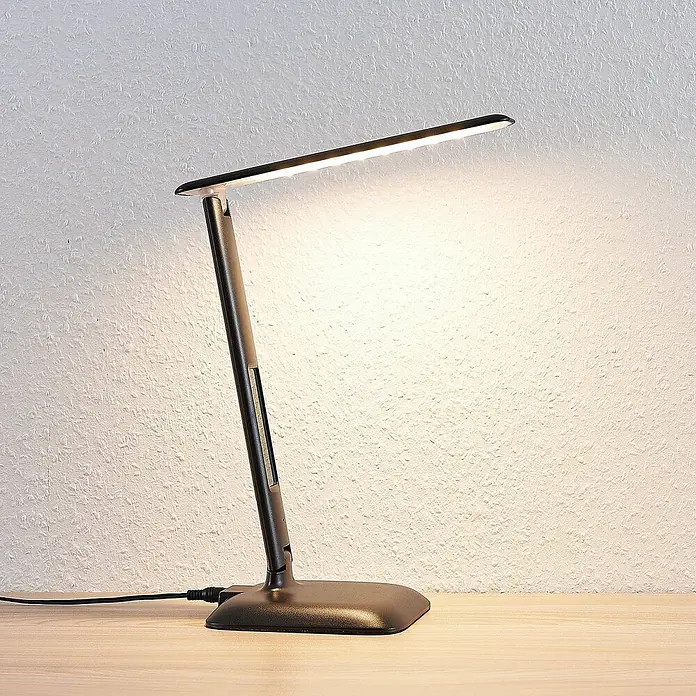Lindby Tischleuchte Ludmilla - L x B x H: 26 x 15 x 34 cm, schwarz, schwarz - Verstellbare dunkelgraue LED-Schreibtischlampe auf einem Holztisch.