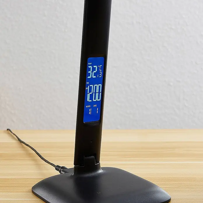 Lindby Tischleuchte Ludmilla - L x B x H: 26 x 15 x 34 cm, schwarz, schwarz - Schwarze Schreibtischlampe mit blauem Digitaldisplay, zeigt 32.3°C, 12:00 Uhr und 11/1 an, auf einem Holzschreibtisch.