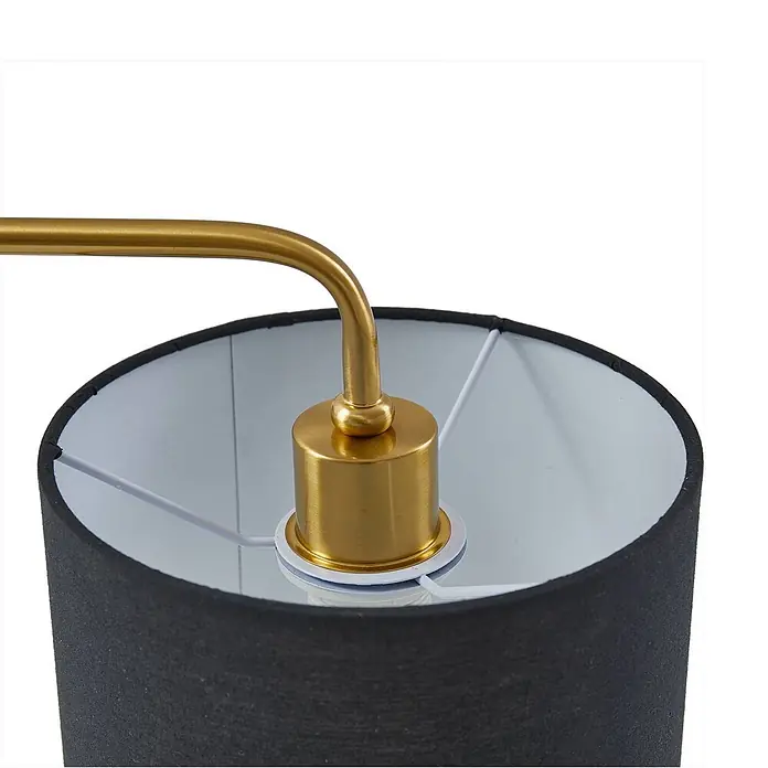 Lindby Tischleuchte Hillary - schwarz, schwarz, E27 - Nahaufnahme einer Lampe mit goldenem Metallarm und Fassung, verbunden mit einem schwarzen Stofflampenschirm mit weißer Innenseite.