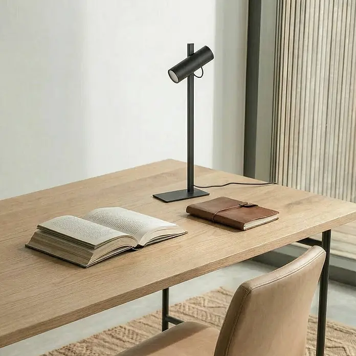 Lucande Tischleuchte Lysias - schwarz, schwarz, GU10 - Elegante schwarze Schreibtischlampe auf einem hellen Holzschreibtisch neben einem offenen Buch und einem braunen Lederjournal.