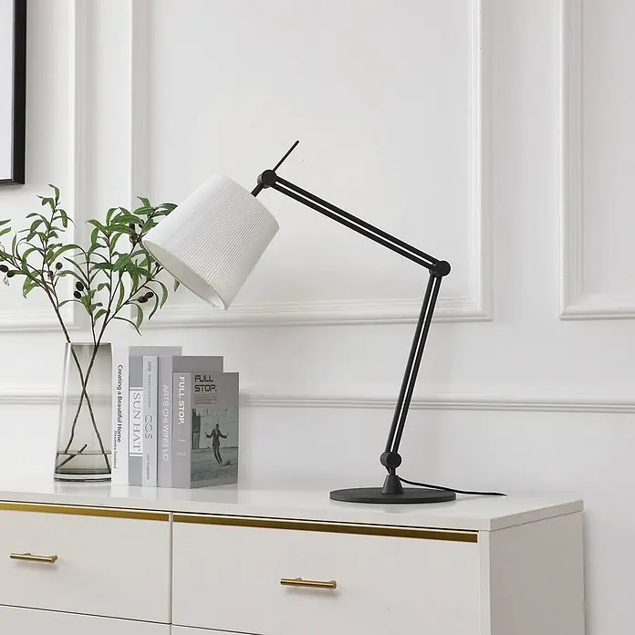 Lucande Tischleuchte Caelia - L x B x H: 22 x 69 x 64,5 cm, schwarz, weiß / opal, E27 - Verstellbare schwarze Schreibtischlampe mit weißem Faltschirm, beleuchtet Bücher und Pflanze auf einer weißen Kommode.