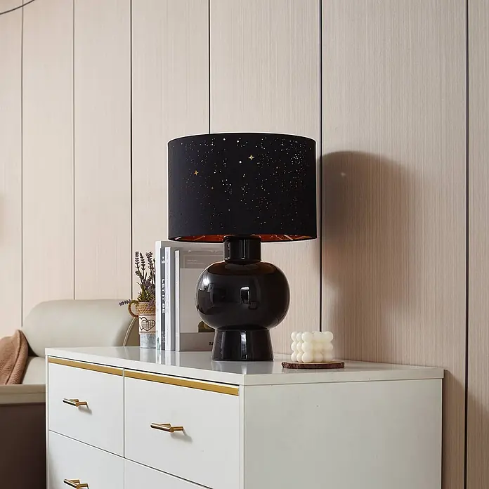 Lindby Tischleuchte Arved - L x B x H: 30 x 30 x 46 cm, schwarz, schwarz, E27 - Schwarze Tischlampe mit Sternen-Lampenschirm auf einer weißen Kommode.