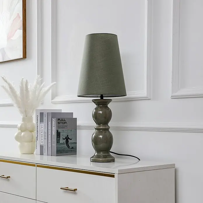 Lucande Tischleuchte Lyndorin - L x B x H: 25 x 25 x 63,1 cm, grün, grün, E27 - Tischlampe in Salbeigrün mit Stoffschirm und Keramikfuß, auf einer weißen Kommode.
