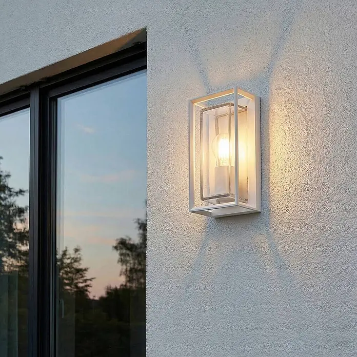 Arcchio Außenwandleuchte Ismera - weiß / opal, weiß / opal, IP65 - Weiße rechteckige Außenwandleuchte mit Klarglas, an strukturierter Außenwand neben einem Fenster montiert, spendet warmes Licht.