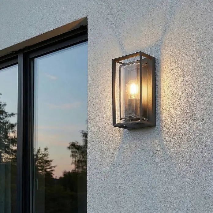 Arcchio Außenwandleuchte Ismera - schwarz, schwarz, IP65 - Moderne Außenwandleuchte mit dunklem Rahmen, Klarglas und warmem Licht, an einer texturierten Außenwand montiert.