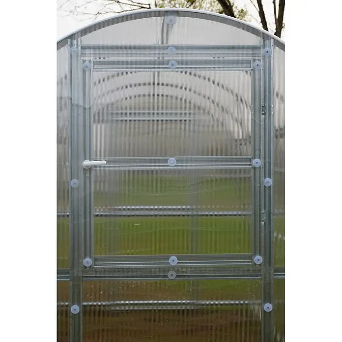 Klasika Greenhouses Gewächshaus Slim Klasika - Außenmaß inkl. Dachüberstand (B x T): 200 x 400 cm, Material Seitenwand: Kunststoff, 4 mm, Silbergrau - Nahaufnahme einer Gewächshausfront aus transparentem Well-Polycarbonat mit Metallrahmen, Türgriff, gewölbtem Dach und grünem Innenraum.