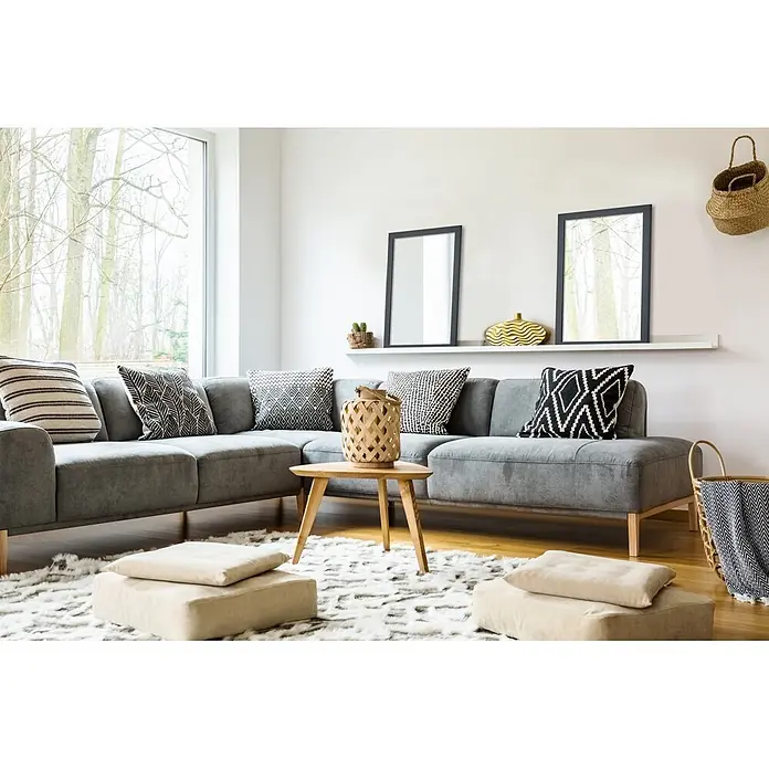 Rahmenspiegel Thea - 48 x 68 cm, Anthrazit, Holz - Ein geräumiges, modernes Wohnzimmer mit einem grauen Ecksofa, einem Holztisch, einem Schaffellteppich und verschiedenen Zierkissen, von Tageslicht durchflutet.