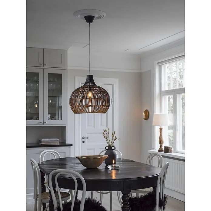 PR Home Pendelleuchte Rattan 50cm - 40 W - Dunkle geflochtene Pendelleuchte über einem rustikalen Esstisch, spendet Licht in einem Esszimmer.