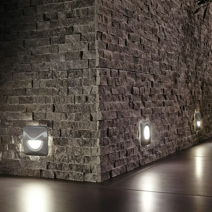 Paulmann Special Line LED-Einbauleuchte - 1,4 W, Weiß, Warmweiß, IP65 - Wandleuchten aus Stein beleuchten einen modernen Raum. Die Leuchten sind quadratisch und geben ein warmes, einladendes Licht ab.