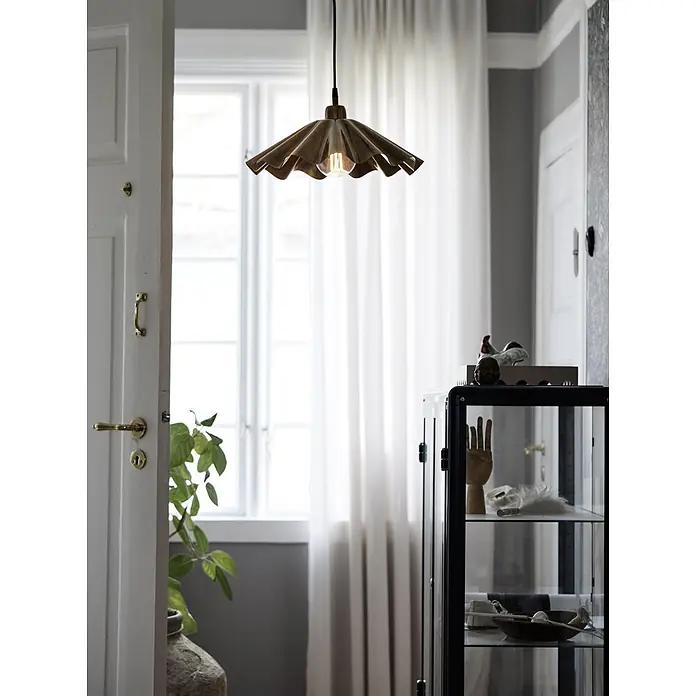 PR Home Pendelleuchte Aira - 40 W, E27 - Gewellte bronzefarbene Pendelleuchte hängt in einem Raum und beleuchtet ihn mit warmem Licht.