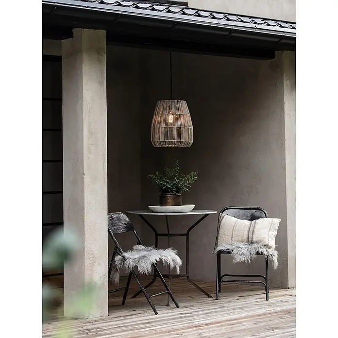 PR Home Pendelleuchte 28cm Outdoor - 15 W, E27 - Gemütliche Outdoor-Sitzgruppe mit rundem Metalltisch und zwei Stühlen, dekoriert mit Kunstfell und Kissen, unter einer Korblampe.