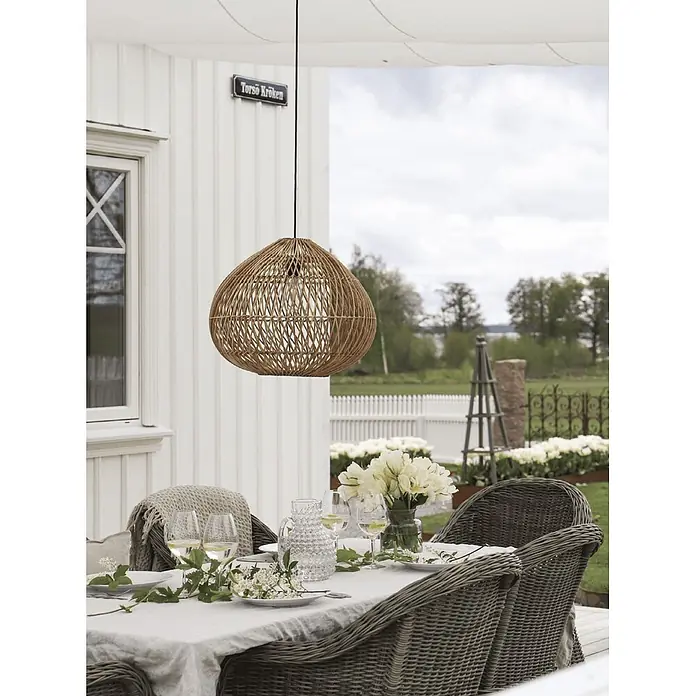 PR Home Pendelleuchte Rattan Outdoor - 15 W, E27 - Natürliche Rattan-Pendelleuchte über einem Esstisch im Freien, die der Terrasse einen rustikalen Akzent verleiht.
