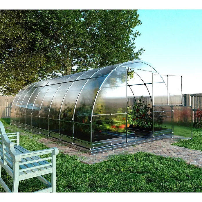 Klasika Greenhouses Gewächshaus Tube Klasika - Außenmaß inkl. Dachüberstand (B x T): 300 x 600 cm, Material Seitenwand: Kunststoff, 6 mm, Silbergrau - Großes gewölbtes Polycarbonat-Gewächshaus mit Metallrahmen im Garten, zeigt wachsende Pflanzen, neben einem gepflasterten Weg und einer Holzbank.