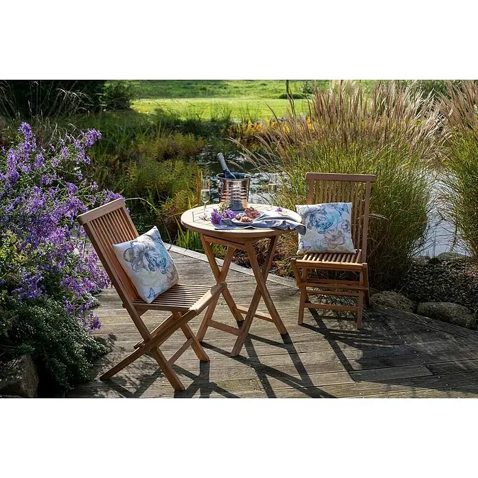 Bene Living Gartentisch-Set Langton & Tisch Sutton - Gesamtumfang: 3 -tlg., Teakholz, Klappbar - Hölzernes Outdoor-Bistro-Set mit rundem Tisch und zwei Stühlen auf einer Terrasse am Teich, mit Getränken.