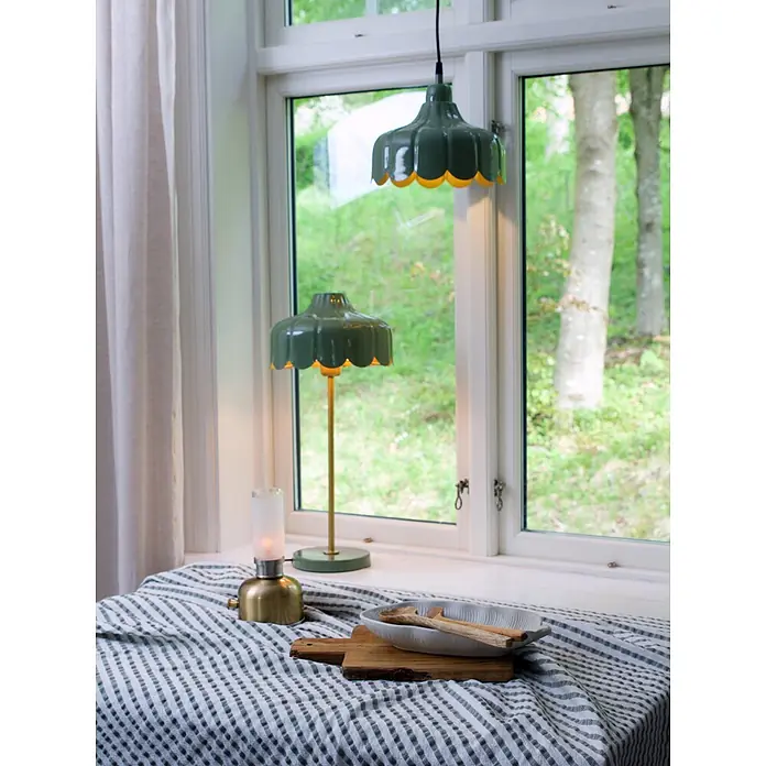 PR Home Pendelleuchte 24cm Fensterleuchte - 25 W, E27 - Zwei grüne Wellenlampen, eine Hänge- und eine Tischlampe, beleuchten einen Fensterbereich mit gestreiftem Tischtuch.