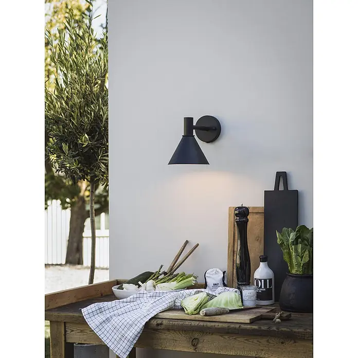 PR Home Außenwandleuchte Mini-Tripp - 15 W, IP44 - Schwarze Wandleuchte an heller Wand, beleuchtet einen Kochbereich im Freien.