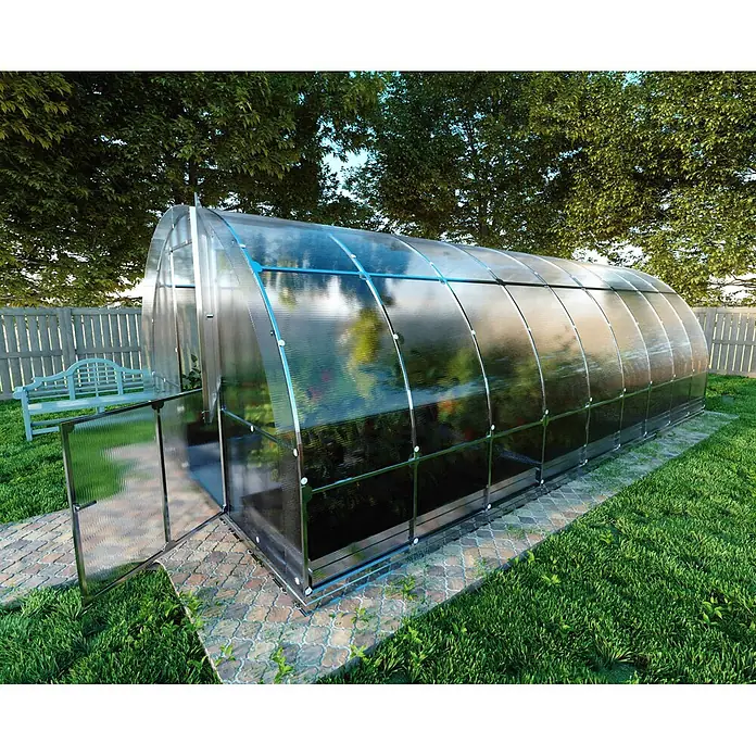Klasika Greenhouses Gewächshaus Tube Klasika - Außenmaß inkl. Dachüberstand (B x T): 300 x 600 cm, Material Seitenwand: Kunststoff, 6 mm, Silbergrau - Ein gewölbtes Gewächshaus aus durchscheinenden Platten und Metallrahmen, auf einem gepflasterten Weg in einem Garten.