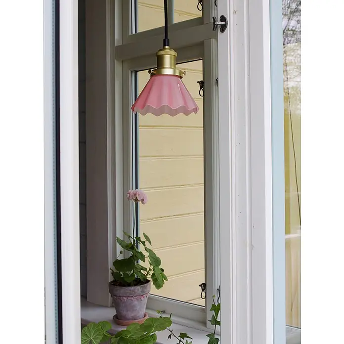 PR Home Pendelleuchte Fensterleuchte - 15 W, L x B x H: 15 x 15 x 16 cm, E27 - Eine rosa geriffelte Glaspendelleuchte mit Messingfassung hängt in einem Fenster, mit einer Topfpflanze auf der Fensterbank.