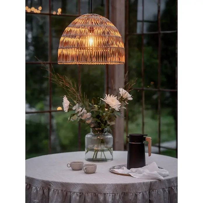 PR Home Pendelleuchte Outdoor - 40 W, E27 - Geflochtene Rattan-Pendelleuchte, die warmes Licht über einem Tisch in Abendstimmung spendet.