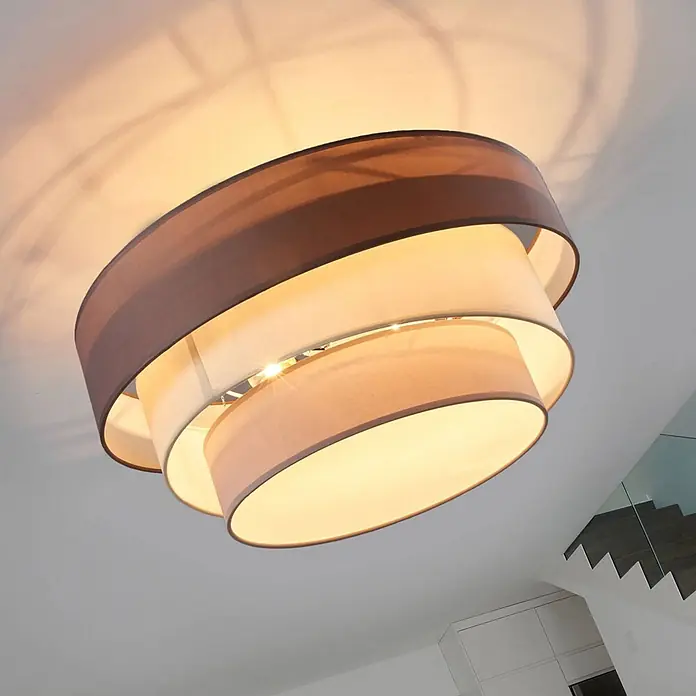 Lindby Deckenleuchte Melia - alu / grau / zink, E27 - Moderne Deckenleuchte mit drei geschichteten Stoffschirmen in Braun- und Beigetönen, beleuchtet, wirft warmes Licht.